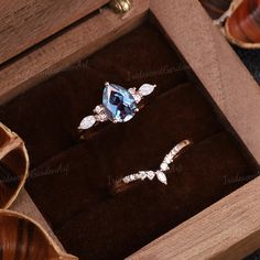 two engagement rings in a wooden box on top of a table with other jewelry items