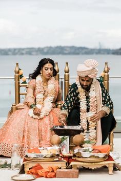 a man and woman sitting next to each other in front of a table with food on it