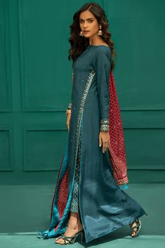 Pakistani Eid Dresses in Blue Long Kameez Trouser Style is all set to grab your attention with formal eid dresses. You can buy lavish fancy wear online to adorn your special event look in an elegant way. Shirt: This lavish festive attire is showing its grace with elegant blue and green color embroidered panels for a shirt. The chiffon shirt is embellished with embroidered front and printed back panel. The neck is designed with a raw silk embroidered neckline. Schiffli embroidered sleeves are des Silk Long Shirt Designs Pakistani, Fancy Long Shirts Pakistani, Long Shirt Design For Women Pakistani, Pakistani Eid Dresses, Long Kameez, Pink Dupatta, Festive Attire, Kameez Designs, Silk Pant