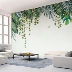 a living room with white furniture and green leaves on the wall behind it is a coffee table