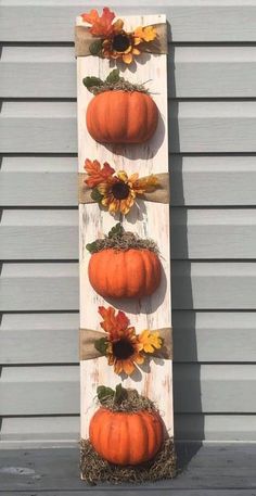 a wooden sign with pumpkins and sunflowers hanging on it's sides