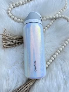 thermos bottle is laying on top of a white fur covered surface with beads