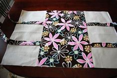 a piece of fabric is laying on top of a table with flowers and squares in the center