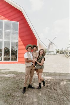 a man and woman standing in front of a red barn with a windmill behind them