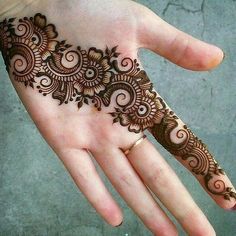 a woman's hand with henna tattoos on it, showing the intricate design