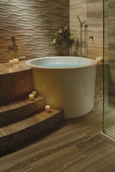 a bath tub sitting on top of a wooden floor next to a walk in shower