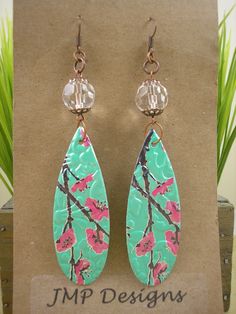 the earrings are decorated with pink flowers on green leaves and brown hooks, along with glass bead earwires