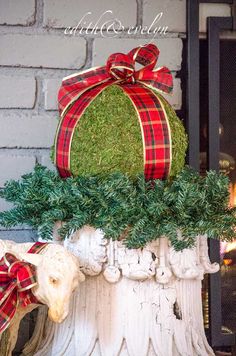 a cow statue with a christmas present wrapped in red and green ribbon sitting on top of it