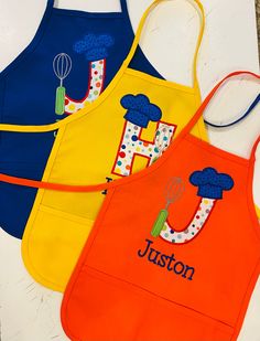 three children's aprons with the word juston on them