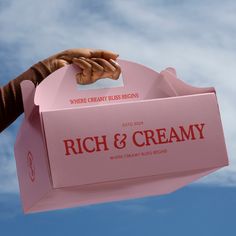 a pink box that says rich & creamy with a hand reaching out to it