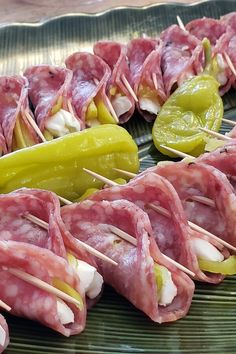 several skewered meats and peppers on a plate with toothpicks in them