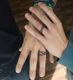 two people with wedding rings on their fingers, one holding the other's hand