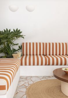 an orange and white striped couch sitting next to a table with a bowl on it