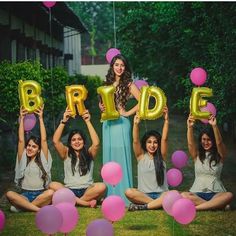 a group of women sitting on the ground holding up balloons