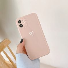 a person holding up a phone case with a heart sticker on the back of it