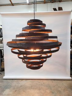 a light fixture hanging from the ceiling in front of a white backdrop with wood strips