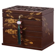 a wooden jewelry box with flowers painted on the side and tassels hanging from it