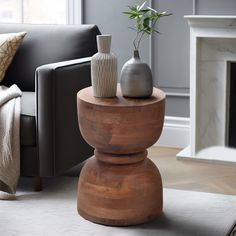 two vases on top of a wooden table in front of a couch and fireplace