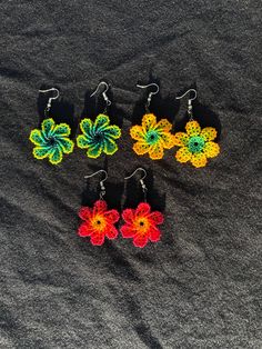 six pairs of flower shaped earrings sitting on top of a black cloth covered tablecloth