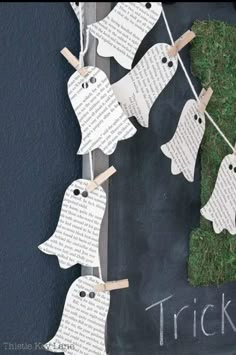 some paper ghost hanging from clothes pins with the words trick written on them and grass