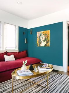 a living room with blue walls and a red couch in the corner, next to a coffee table