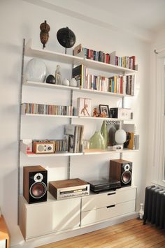 a bookshelf with speakers and other items on it in the corner of a room