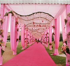 a pink and white wedding ceremony setup with draping, flowers and chandeliers