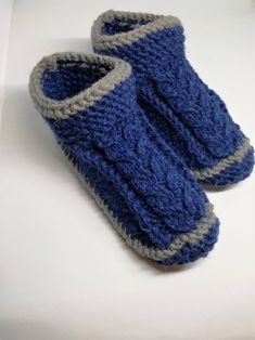 a pair of blue and gray knitted slippers sitting on top of a white surface