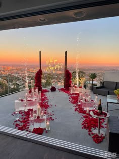 an outdoor wedding setup with candles and rose petals on the floor, overlooking the city