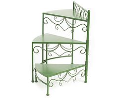 three tiered metal shelf with green paint and wrought iron designs on the top, against a white background