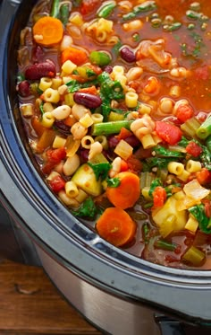 a pot filled with pasta and vegetables on top of a wooden table