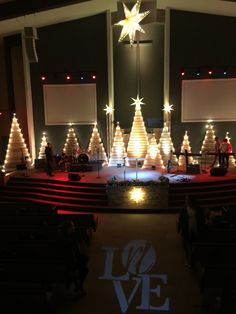 an empty church with christmas trees on the stage