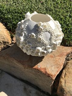 a white vase sitting on top of a pile of rocks