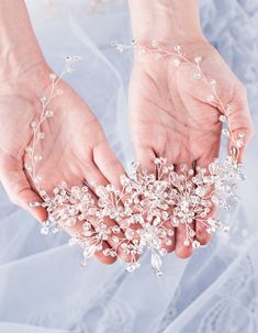 two hands are holding some white flowers on their wedding day and the bride is wearing a tiara