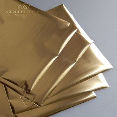 several pieces of shiny gold foil on a white table top, with one folded up in the middle