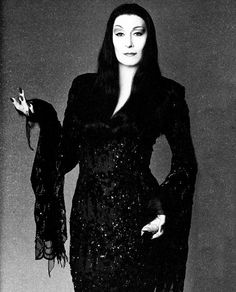 a woman in a black dress is holding her hands out and posing for the camera