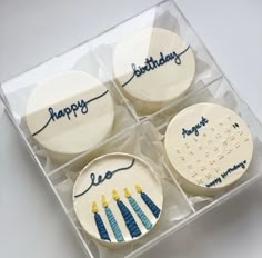 four birthday cupcakes in a clear box with blue frosting and writing on them