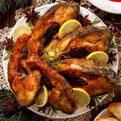 fried fish and lemons on a plate with rosemary sprigs, pine cones and cinnamon sticks