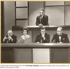 four people sitting at a table in front of microphones and two men standing behind them