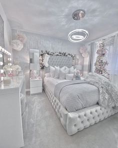 a bedroom decorated in white and silver with christmas decorations on the wall, bed, dresser and mirror