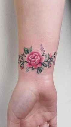 a woman's hand with a pink rose tattoo on the left side of her arm