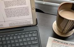 an open laptop computer sitting on top of a desk next to a cup of coffee