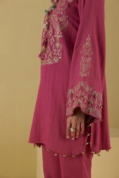 Pink short kurta with floral lurex and thread embroidery on the yoke and sleeves, accentuated with tassels and ghungaroo work. Paired with a bell bottom pant. Components: 2 Pattern: Embroidery Type Of Work: Lurex, Thread, Floral Neckline: Round Neck Sleeve Type: Bell Sleeves Fabric: Rayon Flex Color: Pink Other Details:  Ghungaroo detailed hemline Note: The dupatta shown in the image and the green outfit worn by the other model is not for sale Occasion: Puja - Aza Fashions Kashmiri Kurta, Co Ords Outfits, Aari Design, Short Kurta, Pant Women, Classy Outfits For Women, Woman Outfit, Pant For Women, Embroidery Designs Fashion