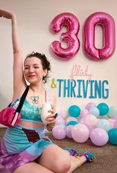 a woman sitting on the floor with her arms in the air and holding a drink