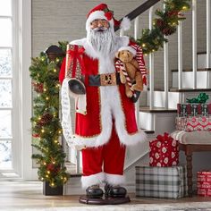 a man dressed as santa claus holding a teddy bear in front of some christmas decorations