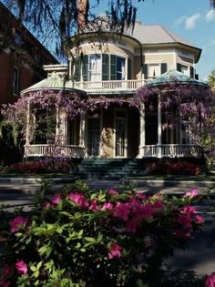 a large house with lots of flowers in front of it