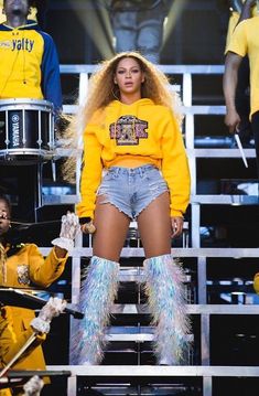 an instagramted photo of a woman in yellow shirt and denim shorts on stage