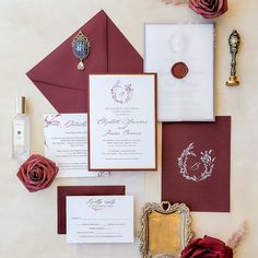 the wedding stationery is laid out on top of each other, including red roses