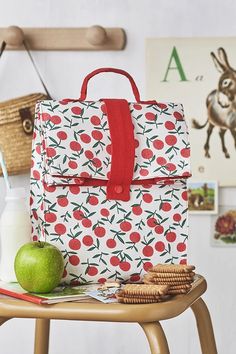 a lunch bag sitting on top of a table next to an apple and crackers