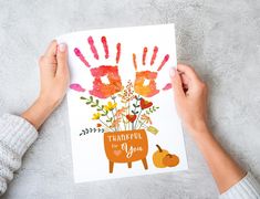 two hands holding up a card with the words thank you on it and flowers in a pot